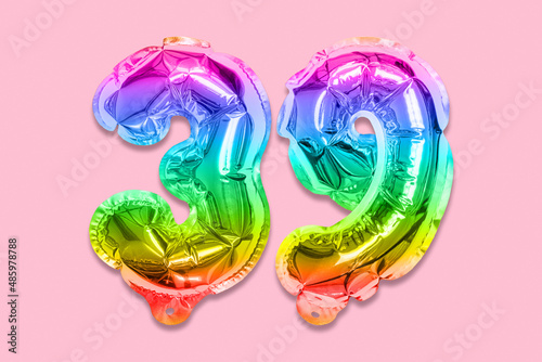 Rainbow foil balloon number, digit thirty nine on a pink background. Birthday greeting card with inscription 39. Top view. Numerical digit. Celebration event, template. photo
