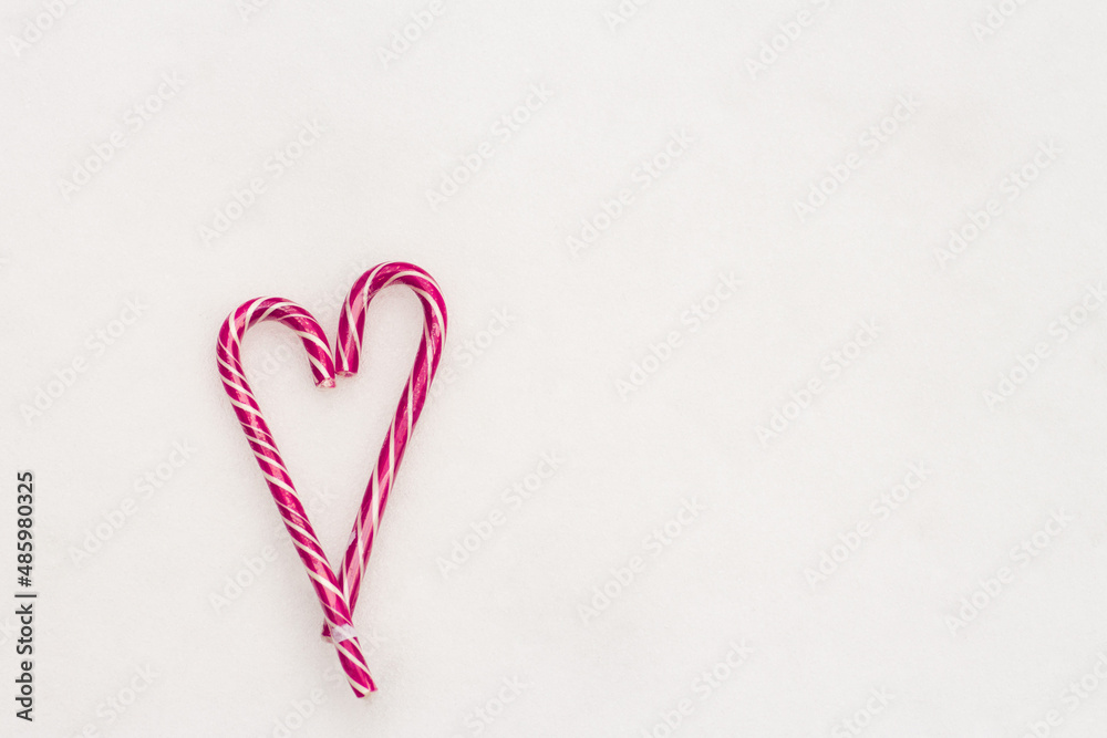 Festive minimalistic white background. A heart of sweet pink striped candies on a white snow background. Love. Valentine. Creative gift ideas for Valentine's Day. The 14th of February. Photo with a Festive minimalistic white background. A heart of sweet pink striped candies on a white snow background. Love. Valentine. Creative gift ideas for Valentine's Day. The 14th of February. Photo with a