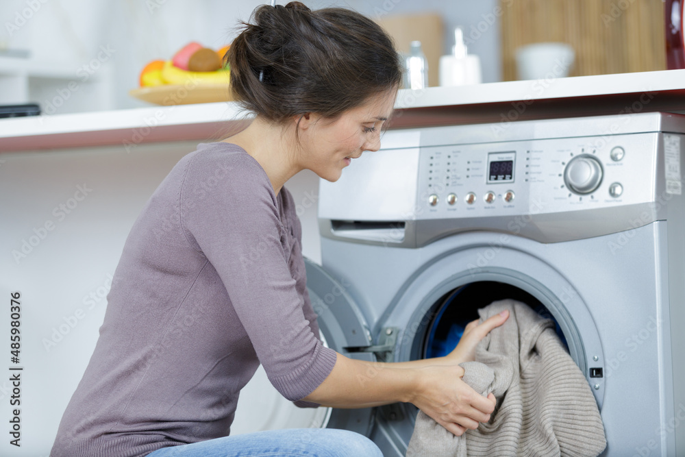 woman putting cloths into the washing machine woman putting cloths into the washing machine