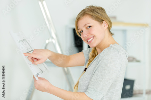 interior designer pointing to plans and smiling at camera