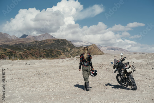 Woman motorcyclist in area of active volcano Shiveluch. Dry river desert. Post-apocalyptic landscape, Kamchatka