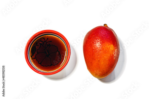 Fresh juicy red-orange mango and tea in a red-orange bowl isolated on a white background, close-up