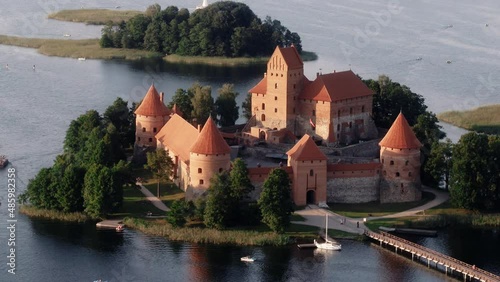 Drone camera view of Trakai Castle located in Lithuania Europe. Old red Castle visible from far away using long lens. Camera moving backwards. Prores codec. photo