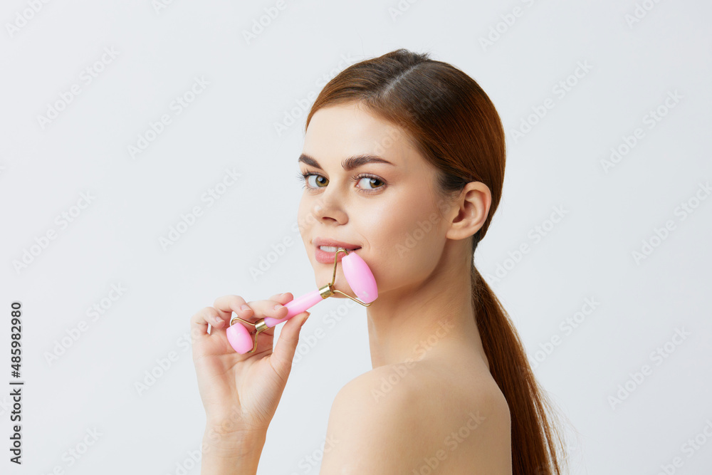 young woman massage roller anti aging facial treatment light background young woman massage roller anti aging facial treatment light background