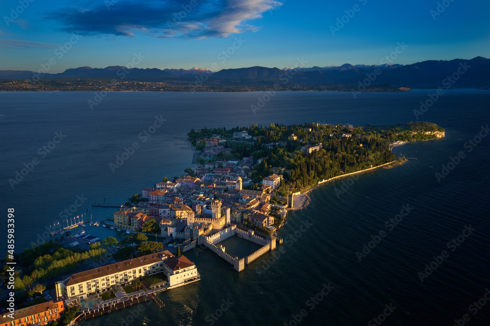 Aerial view of Sirmione. Sirmione Castle, Lake Garda, Italy. The flag of Italy on the main tower of the castle. Aerial photography with drone, Rocca Scaligera Castle in Sirmione. Garda, Italy. 