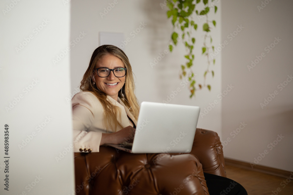 Young woman working at home with laptop and papers on desk and headphones. Home office concept. Young woman working at home with laptop and papers on desk and headphones. Home office concept.