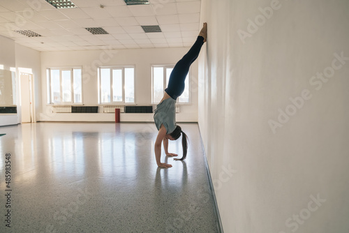 Woman doing yoga exercise near big mirror in empty yoga studio