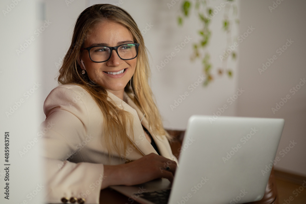 Young woman working at home with laptop and papers on desk and headphones. Home office concept. Young woman working at home with laptop and papers on desk and headphones. Home office concept.