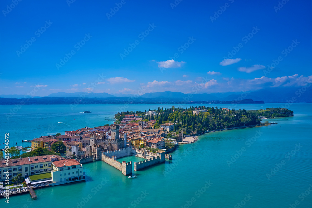 The flag of Italy on the main tower of the castle. 
Aerial photography with drone, Rocca Scaligera Castle in Sirmione. Garda, Italy. Aerial view of Sirmione. Sirmione Castle, Lake Garda, Italy.
