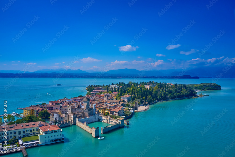 Sirmione Castle, Lake Garda, Italy. The flag of Italy on the main tower of the castle. Aerial photography with drone, Rocca Scaligera Castle in Sirmione. Garda, Italy. Aerial view of Sirmione. 