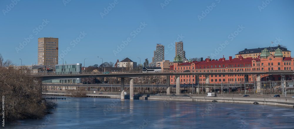 Panorama view the canal Karlbergskanalen with ice floats and an arched traffic route bridges a sunny winter day in Stockholm