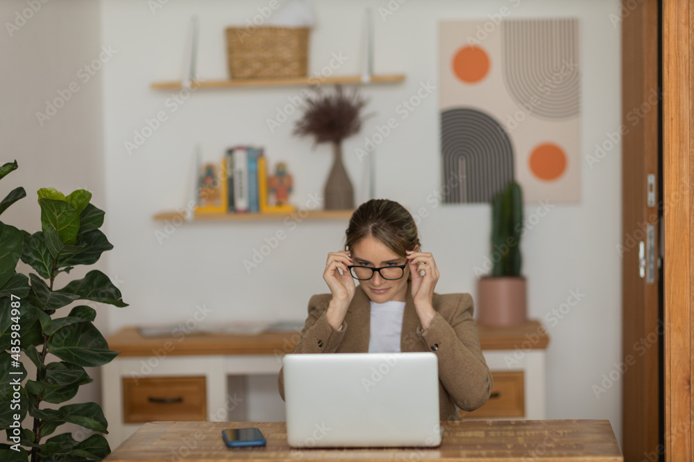Young woman working at home with laptop and papers on desk and headphones. Home office concept. Young woman working at home with laptop and papers on desk and headphones. Home office concept.