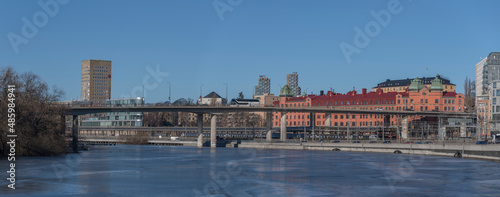 Panorama view the canal Karlbergskanalen with ice floats and an arched traffic route bridges a sunny winter day in Stockholm