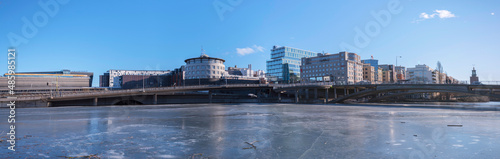 Panorama view, offices, hotels and the central station at the canal Karlbergskanalen with ice floats and an arched walk path and the traffic route Karlbergsleden, Stockholm