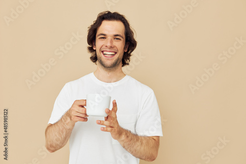man in a white T-shirt with a mug in hand isolated background