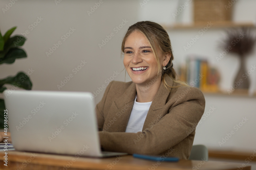 Young woman working at home with laptop and papers on desk and headphones. Home office concept. Young woman working at home with laptop and papers on desk and headphones. Home office concept.