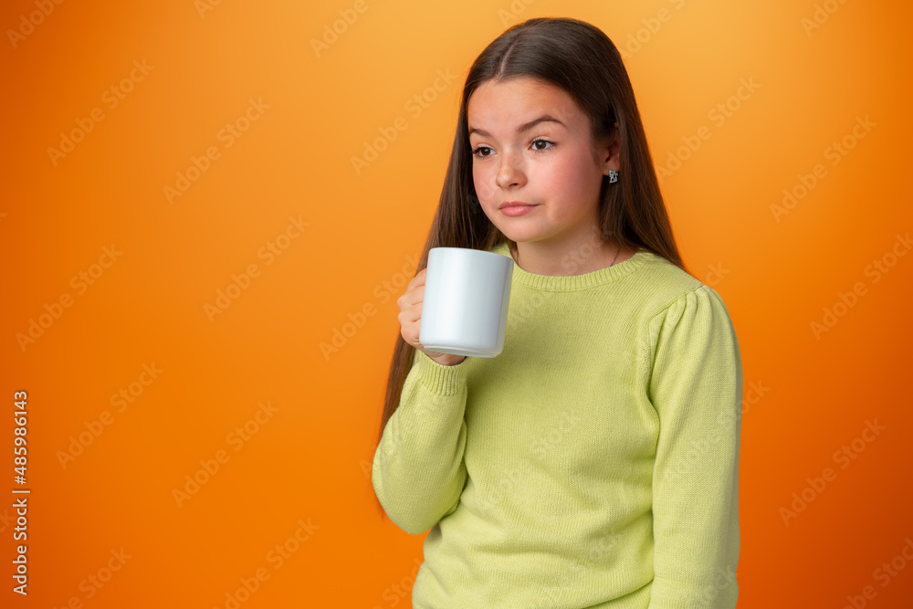 Sleepy teenager girl holding a hot cup of coffee on orange background Sleepy teenager girl holding a hot cup of coffee on orange background