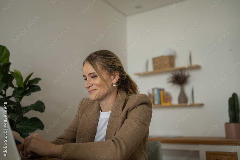 Young woman working at home with laptop and papers on desk and headphones. Home office concept. Young woman working at home with laptop and papers on desk and headphones. Home office concept.