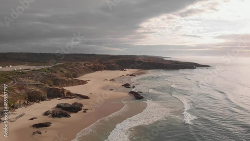 Remote golden sand beach on Atlantic coastline, Portugal; aerial pullback photo