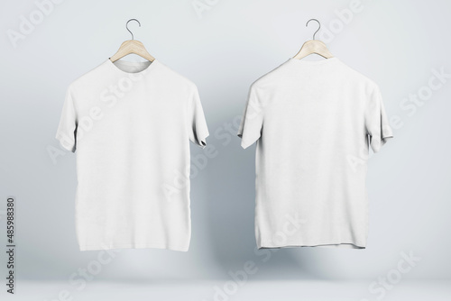 Advertising concept with two blank white t-shirts on wooden hangers with copyspace for your text on abstract light background. 3D rendering, mockup