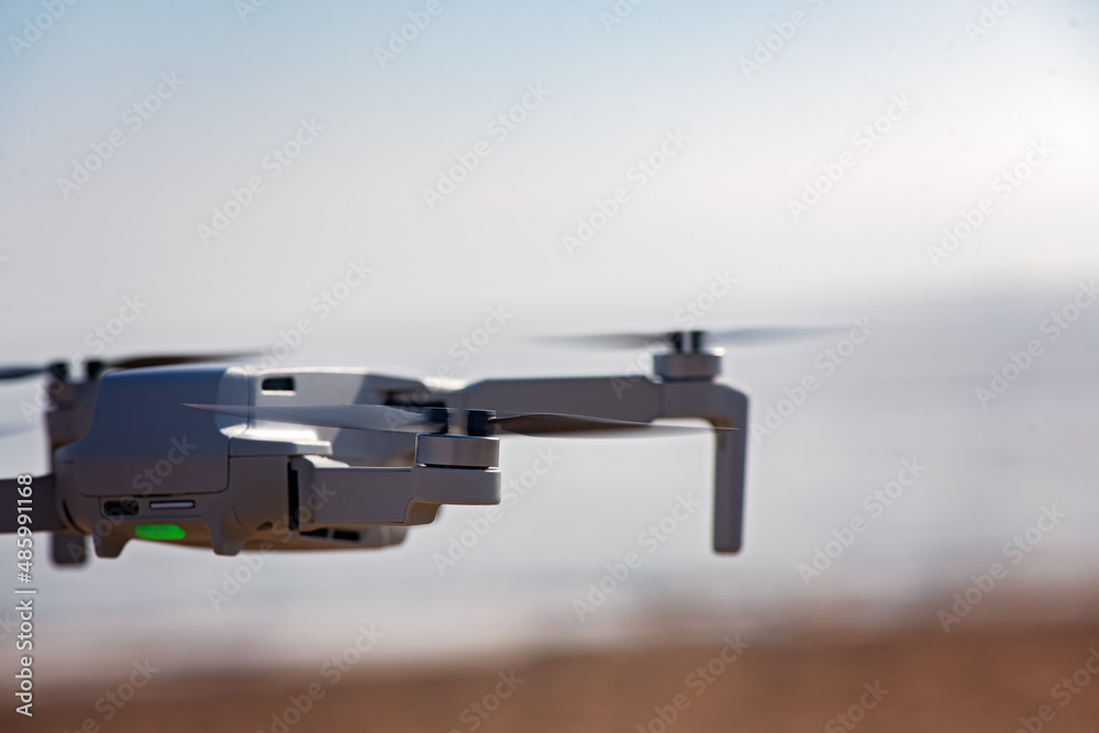Fototapeta premium Quadcopter flight at sunset on the seashore. Drone in the sky