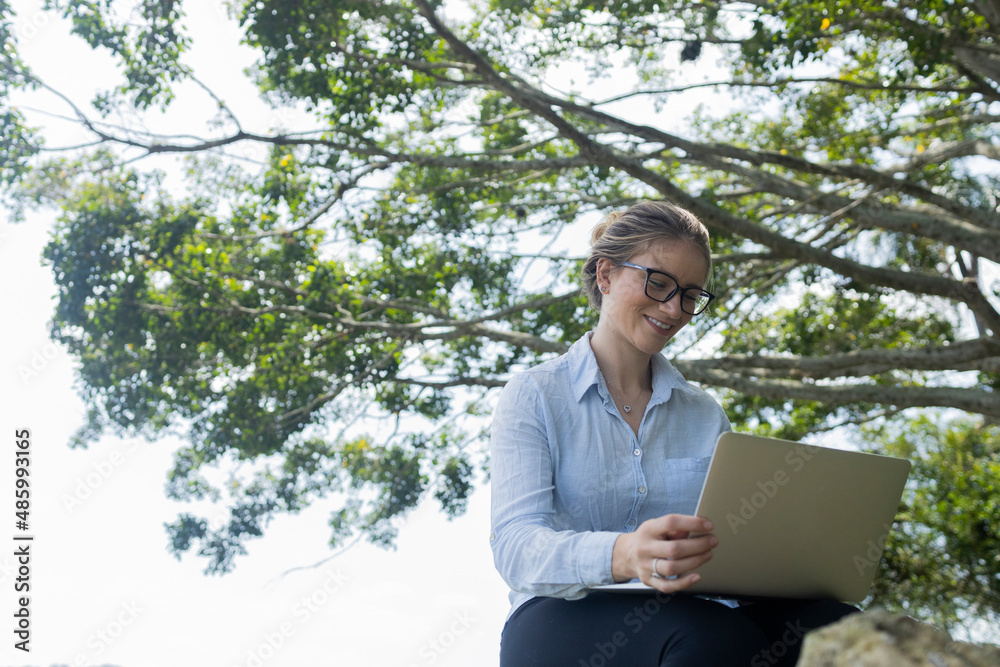 Young woman using a laptop at day time with a green park in the background. High quality photo Young woman using a laptop at day time with a green park in the background. High quality photo
