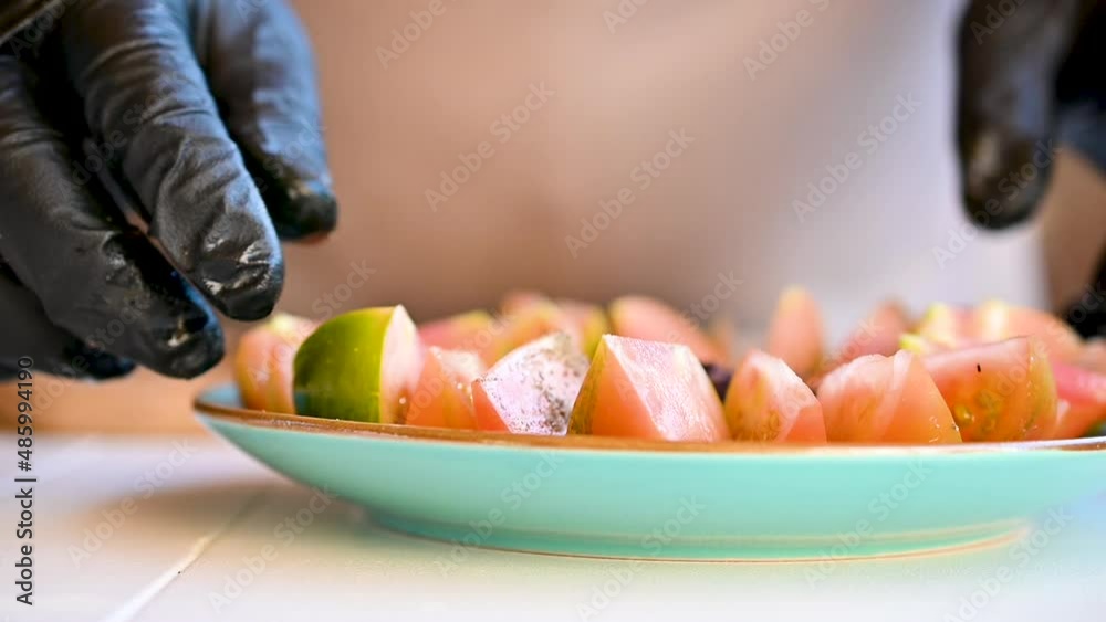 Chef in gloves prepares a tomato appetizer, serving