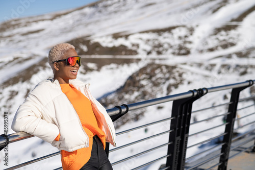 A African American woman wearing goggles standing in snowy mountain during winter
