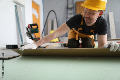 Handyman set wooden panel of laminate floor, installing floor in flat