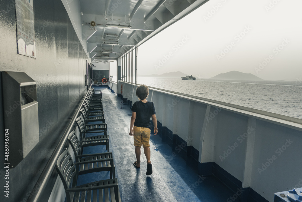 Fototapeta premium Little boy along chairs on passenger ferry