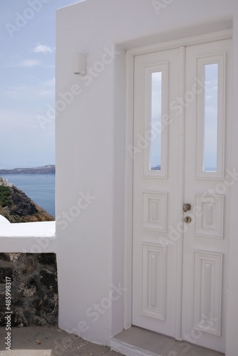 A beautiful whitewashed door with a view to the aegean sea and the blue sky in Santorini Greece © DIMITRIOS