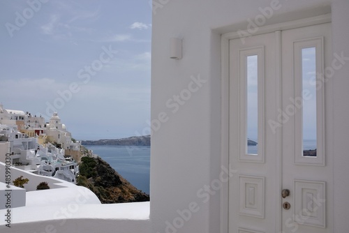 A beautiful whitewashed door with a view to the aegean sea and the blue sky in Santorini Greece