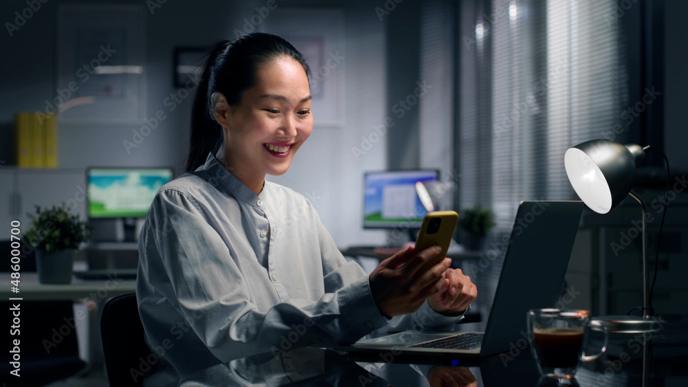 Chinese businesswoman at work having video call on smartphone. Portrait of Chinese female manager working on laptop and chatting on video conference in office. Chinese businesswoman at work having video call on smartphone. Portrait of Chinese female manager working on laptop and chatting on video conference in office.