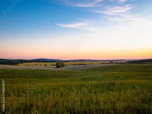 Fields forest and mountains at sunset. Beautiful nature. Landscape for posters and banners.