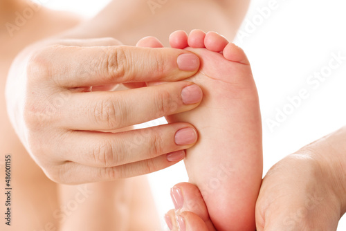 Mother massaging little child's feet and soles.