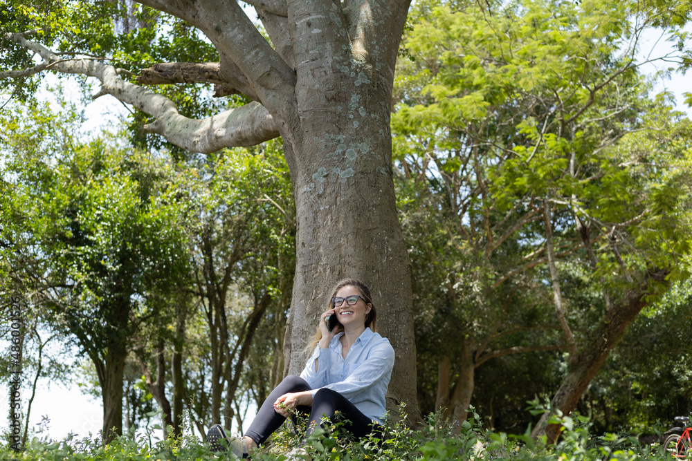 Young woman using a smartphone at day time with a green park in the background. High quality photo Young woman using a smartphone at day time with a green park in the background. High quality photo