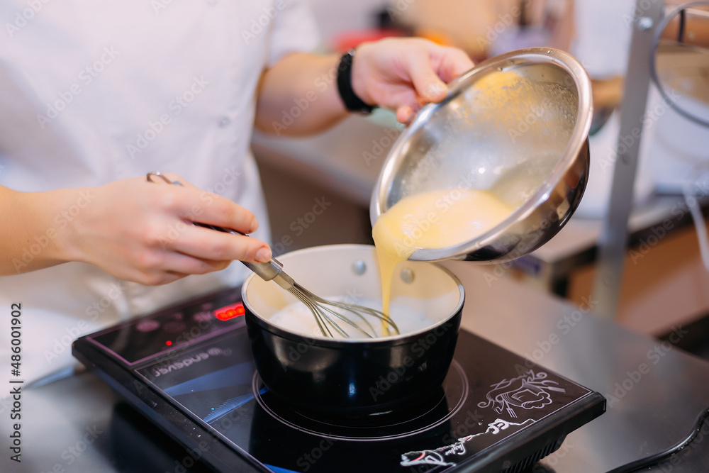 Pastry chef girl cooks custard on an induction cooker