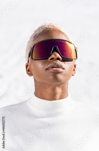 A African American woman with sunglasses sitting on snowy ground during winter