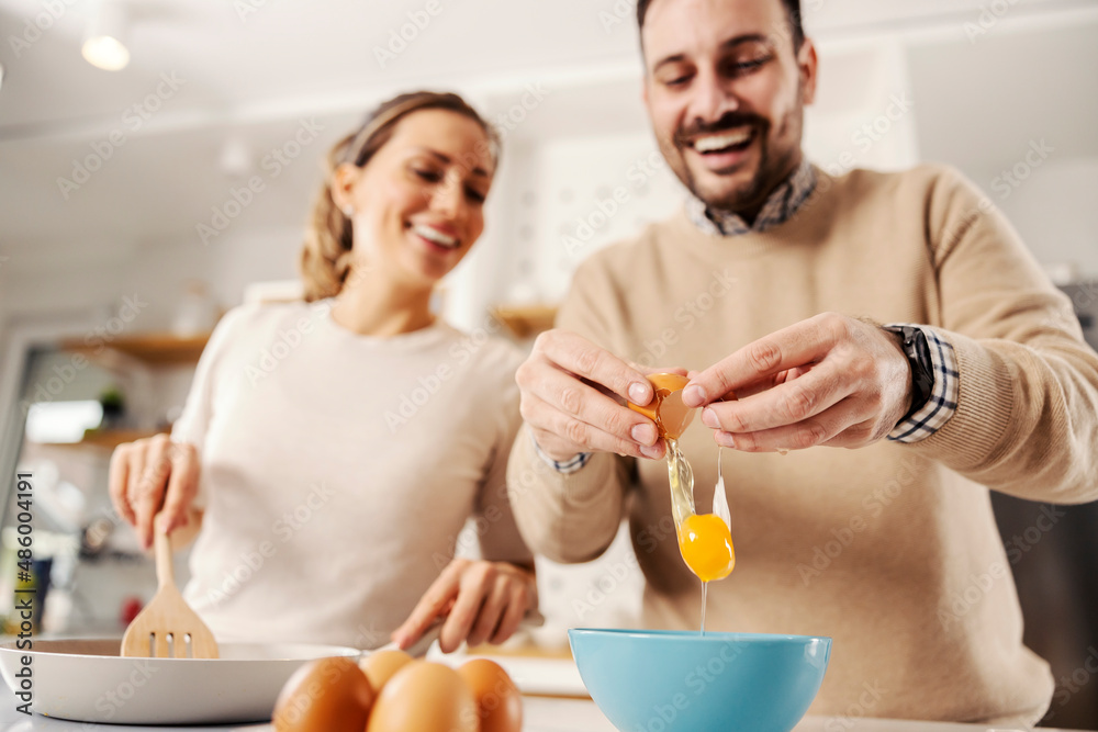 Close up of a man breaking the egg in the kitchen. Couple preparing breakfast together. Close up of a man breaking the egg in the kitchen. Couple preparing breakfast together.