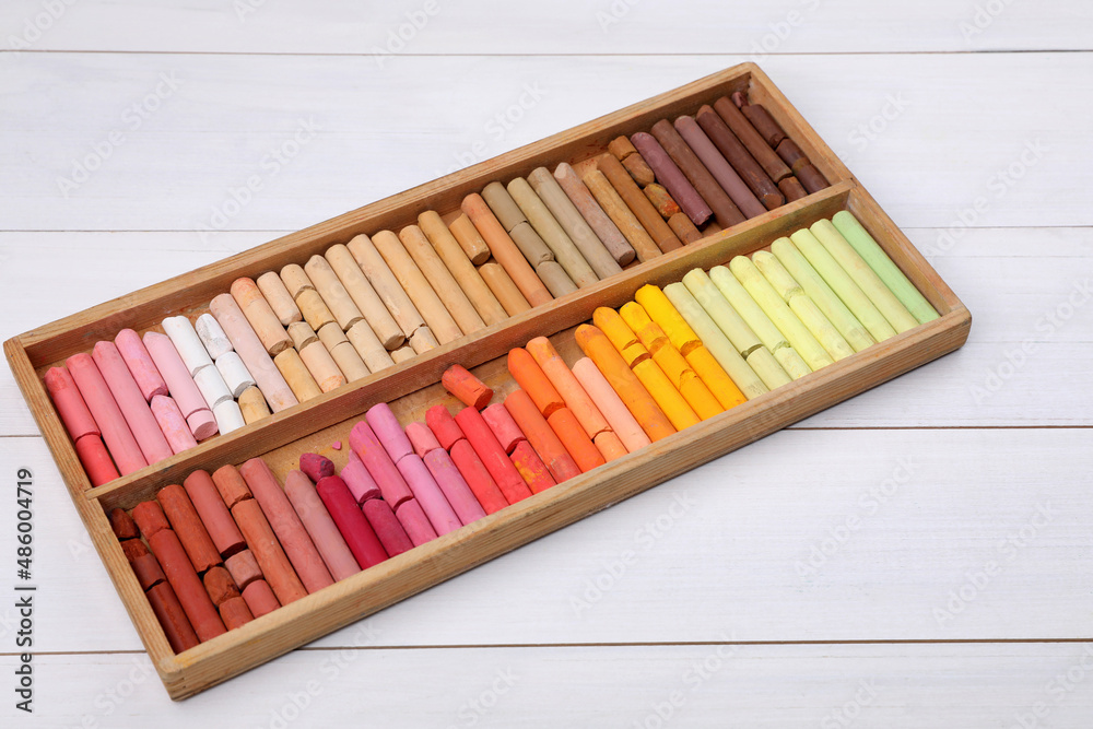 Set of soft pastels in box on white wooden table. Drawing material Set of soft pastels in box on white wooden table. Drawing material