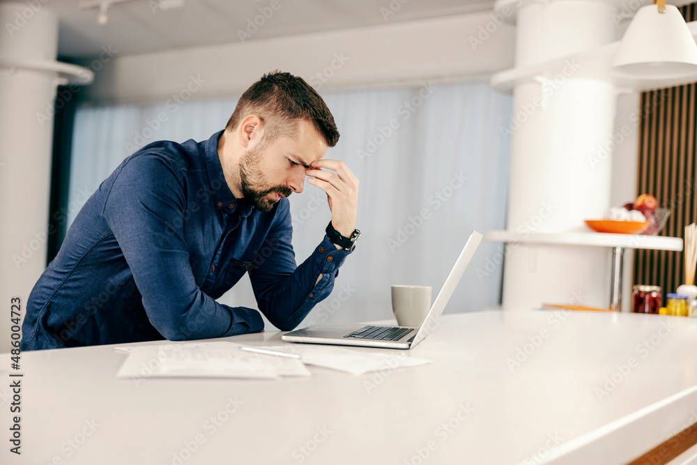 An unhappy man having problems with finances while looking at the laptop at home. An unhappy man having problems with finances while looking at the laptop at home.