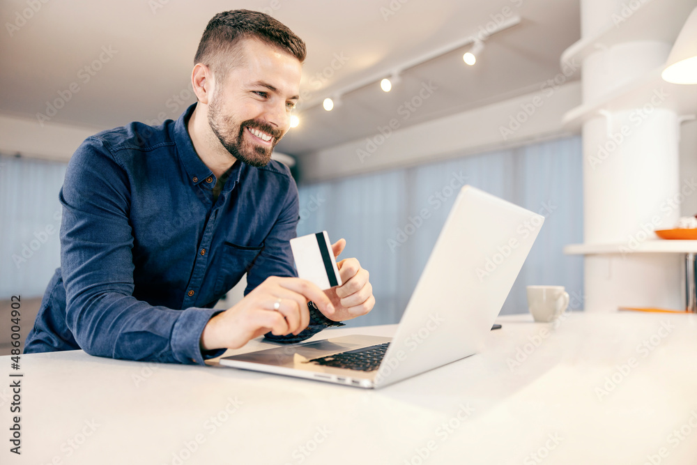 A happy man shopping online on his laptop from his comfortable home. A happy man shopping online on his laptop from his comfortable home.