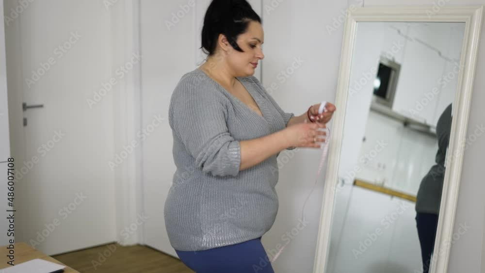 Young overweight woman feeling happy after measuring her waist at home Young overweight woman feeling happy after measuring her waist at home