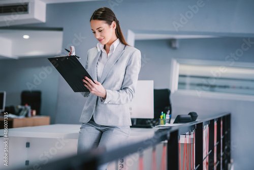 A businesswoman checking on paperwork at modern office.