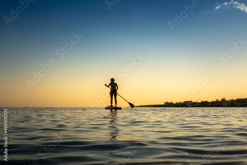 Woman stand up paddle boarding on sea against sky