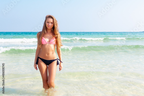 Young attractive blonde girl with perfect sport body in bikini on the tropical summer beach
