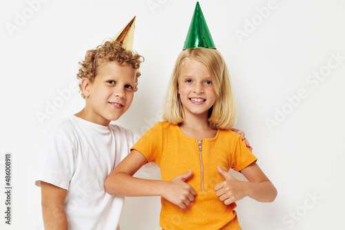 picture of positive boy and girl with caps on his head holiday entertainment light background