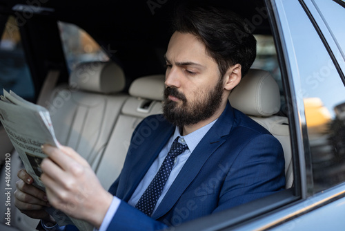 A handsome young businessman in a suit outdoors using his mobile phone is driving in the car © Milana