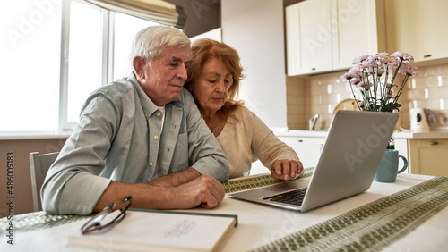Elderly caucasian couple use and watch on laptop