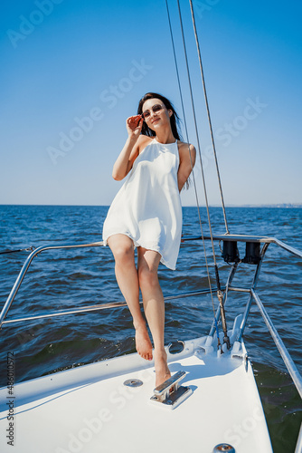 Full size of beauty girl in white dress who enjoys walk on the yacht. Luxury resort. Travel concep